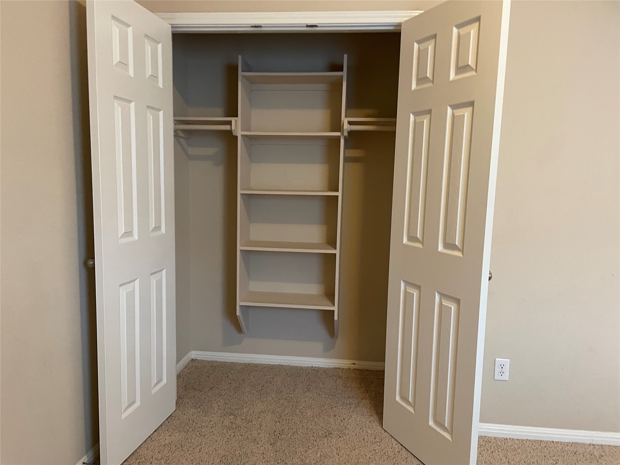 11713 Dunblane Way Austin, TX 78754 - Photo 18 of 22 Reach-in closet featuring bi-fold panel doors, built-in shelving, dual hanging rods, and neutral-toned carpeting