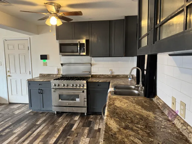 a kitchen with stainless steel appliances granite countertop a stove a sink and a microwave