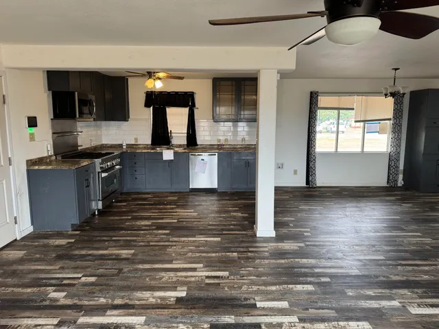 an empty room with wooden floor and stainless steel appliances