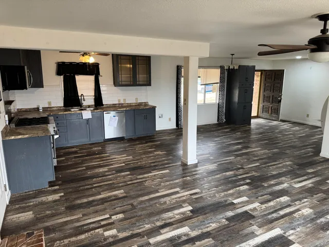 a large kitchen with granite countertop a stove top oven a sink dishwasher and a refrigerator with wooden floor