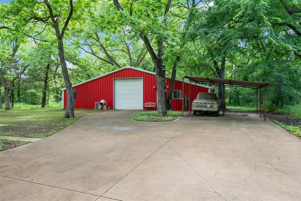 3650 Mt Zion Road Midlothian, TX 76065 - Photo 26 of 38 The 2400 sf metal building is set up in 3 sections. On the right side of the building there is roughly 20 x 40 feet of workshop and office area. The center portion where the large roll down door is located is also 20 x 40. This area has a pull through area with another roll up door on the backside of the building. There is another roll down door on the far left side of the building. That opens up to a gravel floor that is 20 x 40 for parking large equipment such as brush hogs, mowers, etc. There is a walk through door on the front of the building behind the tree, that can't be seen in this photo.