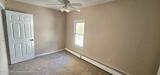 an empty room with windows and fan