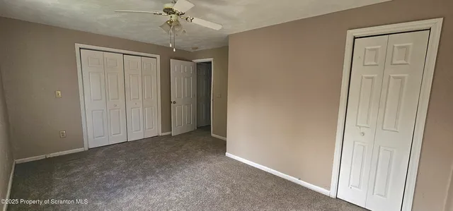 an empty room that has a chandelier fan and closet