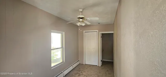an empty room with windows and ceiling fan