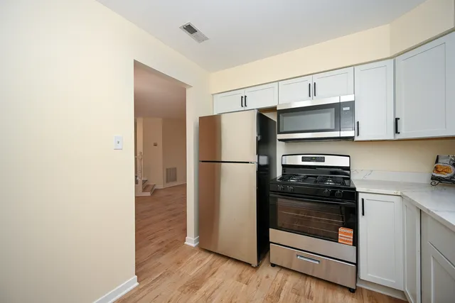 a kitchen with a refrigerator stove and wooden cabinets