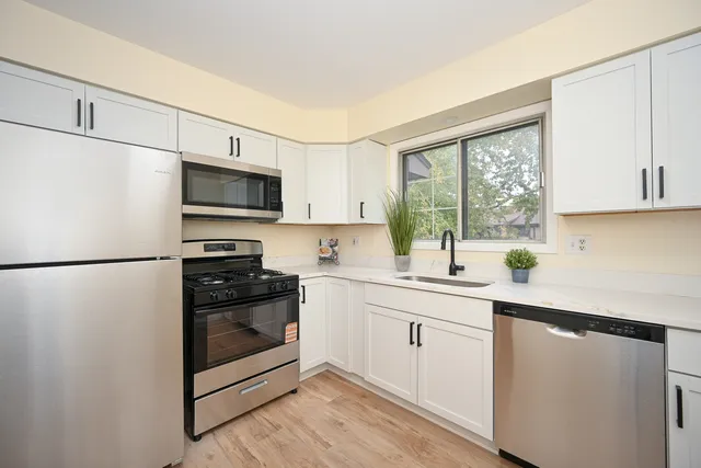 a kitchen with a sink a white cabinets and stainless steel appliances