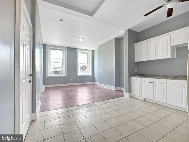 an empty room with wooden floor cabinet and windows