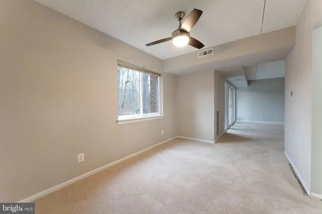 en empty room with windows and ceiling fan