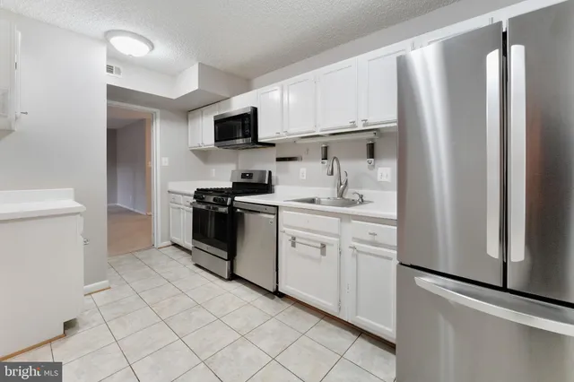 a kitchen with white cabinets and refrigerator