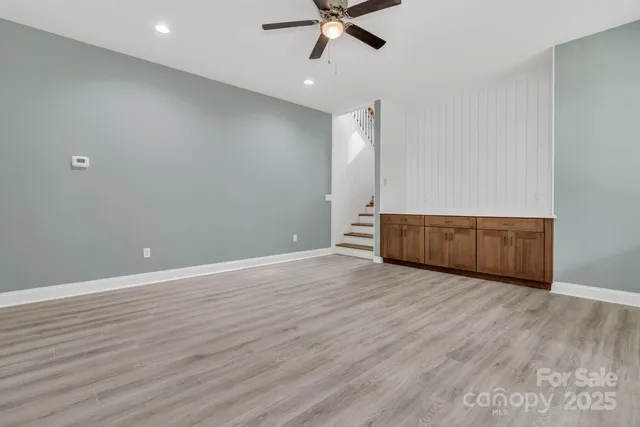 a view of an empty room with wooden floor and a ceiling fan