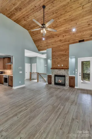 a view of an empty room with wooden floor and a fireplace