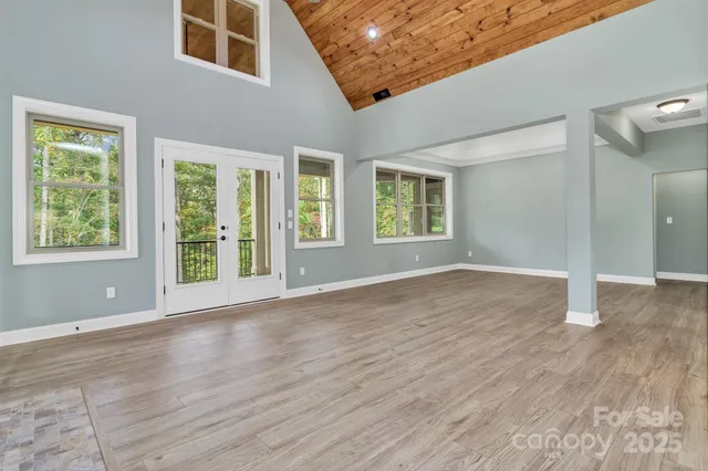 a view of an empty room with wooden floor and windows