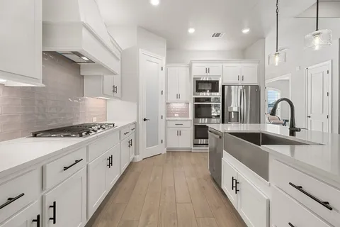 a large kitchen with stainless steel appliances granite countertop a lot of counter space and wooden floors