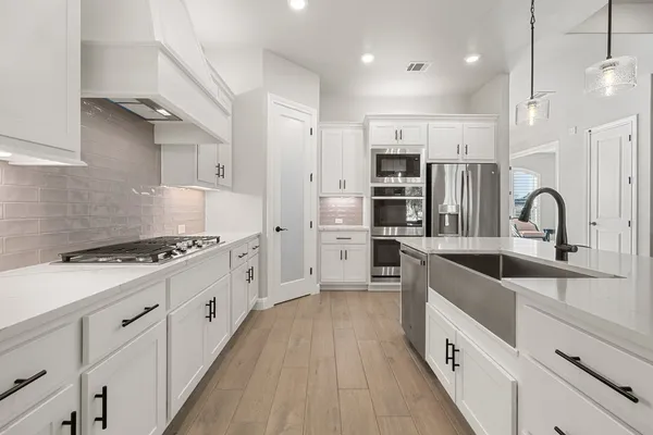 a large kitchen with stainless steel appliances granite countertop a lot of counter space and wooden floors