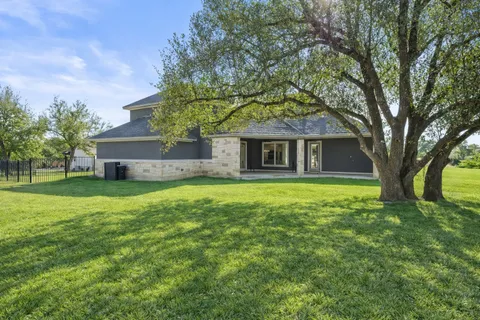 a front view of a house with a garden and tree