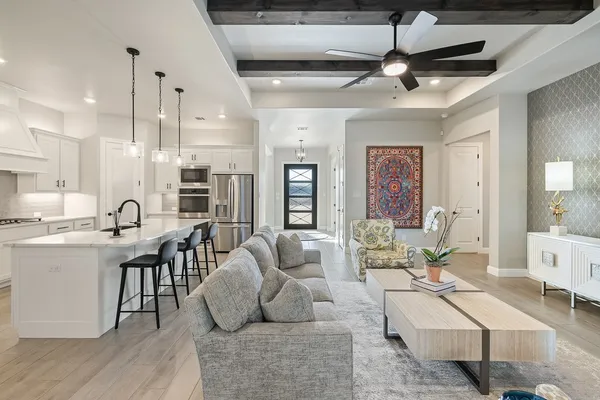 a living room with furniture kitchen view and a chandelier