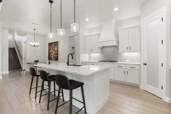 a kitchen with stainless steel appliances kitchen island a chandelier and white cabinets