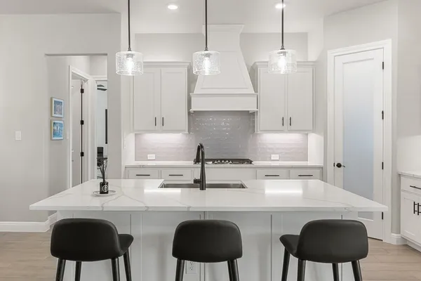 a kitchen with stainless steel appliances a sink a stove a refrigerator and white cabinets