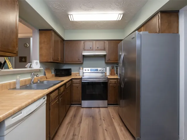 a kitchen with granite countertop a refrigerator stove and sink