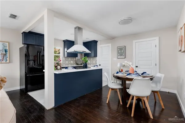 a kitchen with stainless steel appliances a dining table chairs and wooden floor