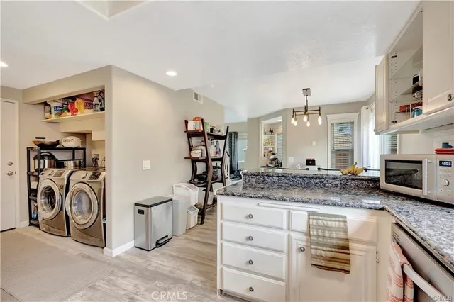 a bathroom with a granite countertop sink and a washing machine