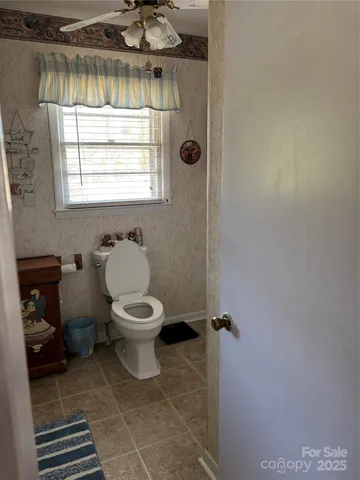a bathroom with a toilet a window and glass door
