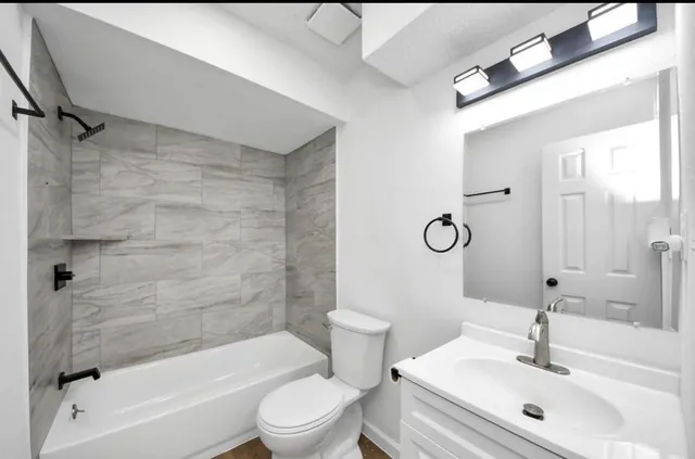 a bathroom with a bathtub shower sink vanity mirror and toilet