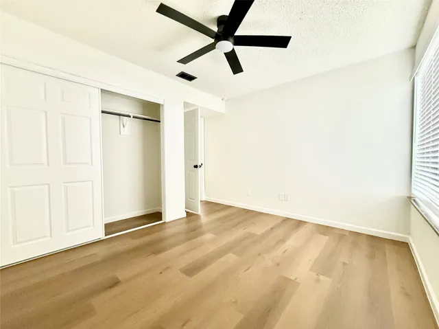 an empty room with wooden floor and a ceiling fan