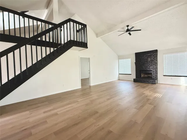 a view of an empty room with wooden floor and a ceiling fan