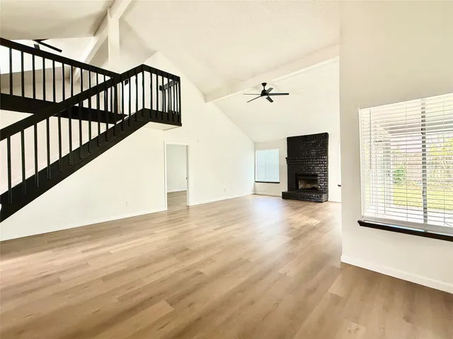 a view of an empty room with a window and wooden floor