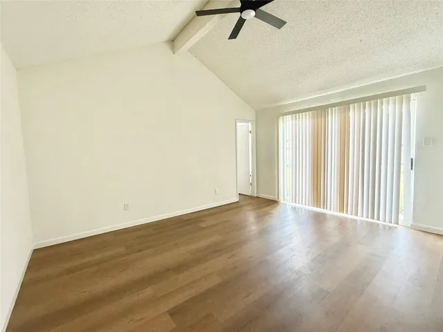 an empty room with wooden floor fan and windows