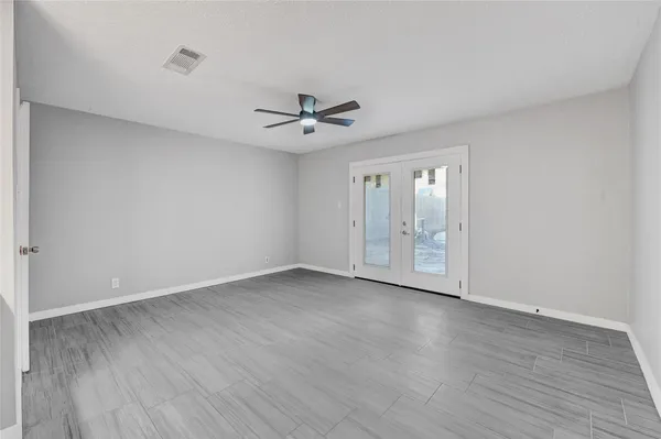 a view of an empty room with chandelier fan and wooden floor