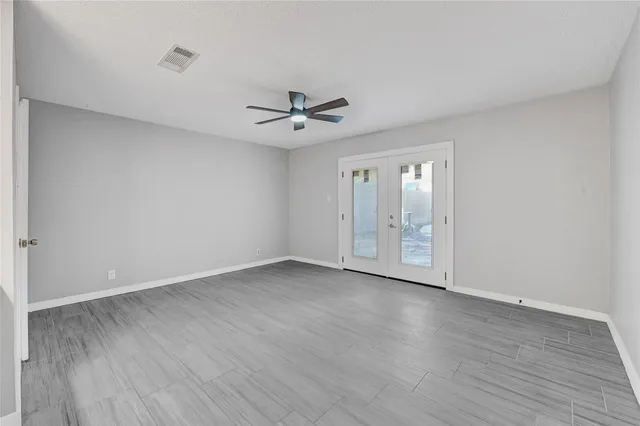 a view of an empty room with chandelier fan and wooden floor