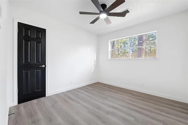 an empty room with wooden floor closet and windows