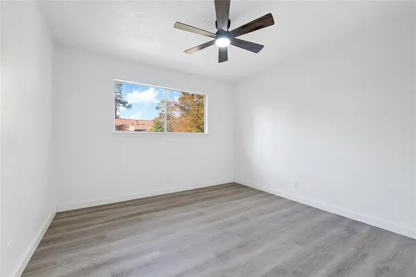an empty room with wooden floor and ceiling fan