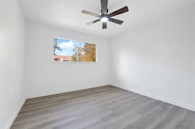 an empty room with wooden floor and ceiling fan