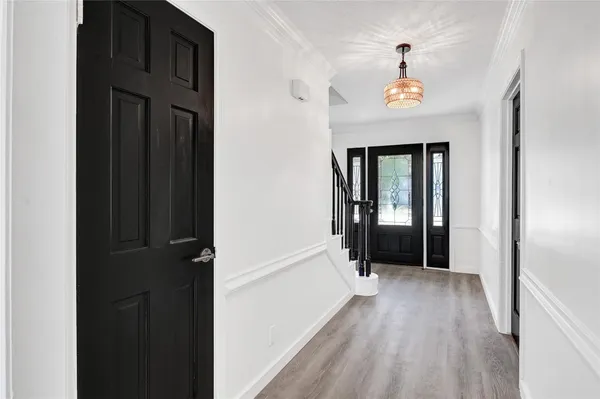 a view of a hallway with wooden floor and a bathroom