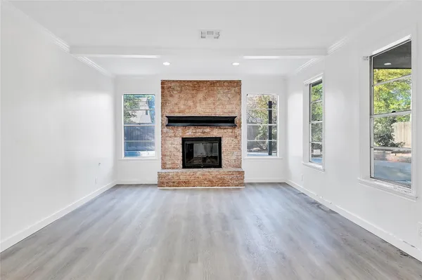an empty room with wooden floor fireplace and windows