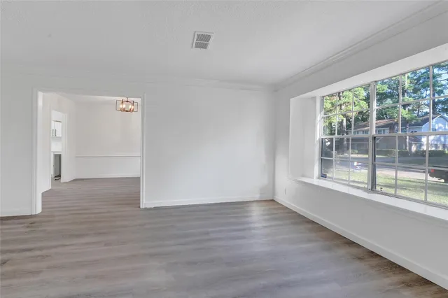 a view of an empty room with wooden floor and a window