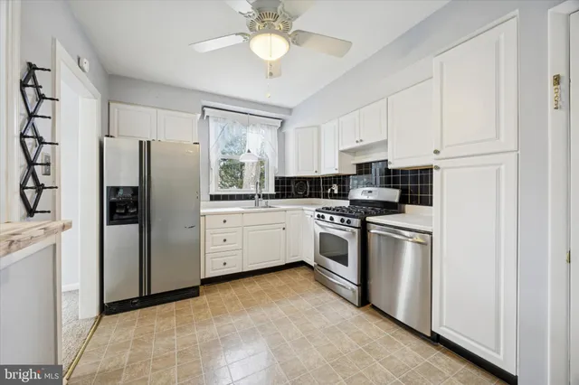 a kitchen with stainless steel appliances a refrigerator sink and white cabinets