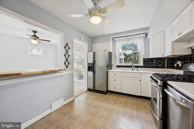 a kitchen with white cabinets and stainless steel appliances