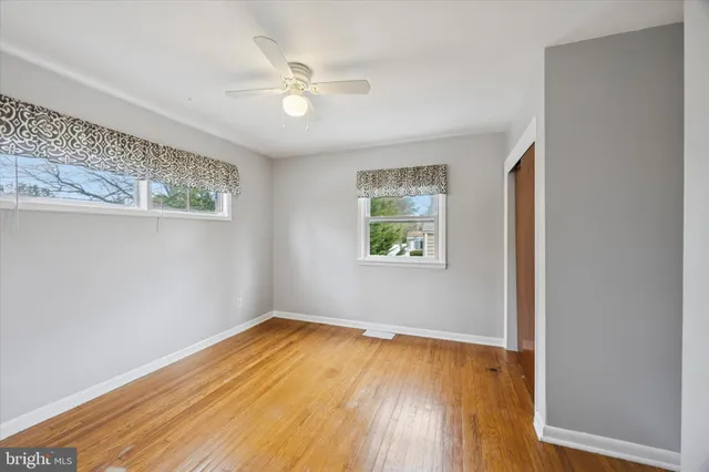 an empty room with wooden floor and fan