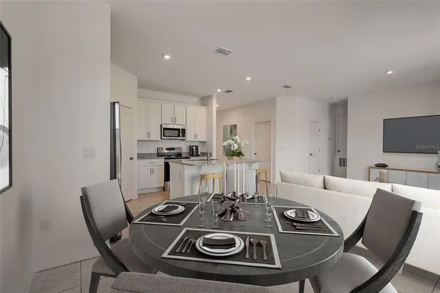 a view of a dining room with furniture a kitchen and chandelier