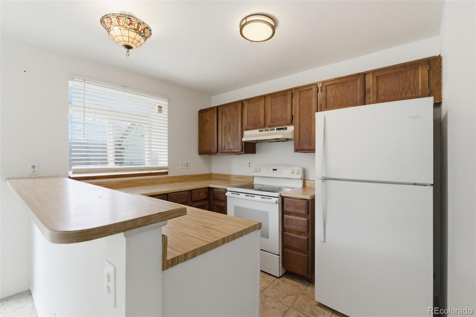 17335 East Rice Circle, Unit C Aurora, CO 80015 - Photo 8 of 14 a kitchen with granite countertop a refrigerator a sink a stove and a window