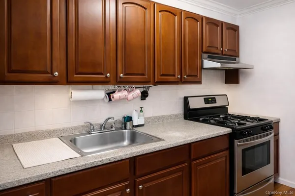 a kitchen with granite countertop a sink a stove and cabinets