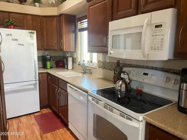 a kitchen with a sink dishwasher a refrigerator a stove and white cabinets with wooden floor