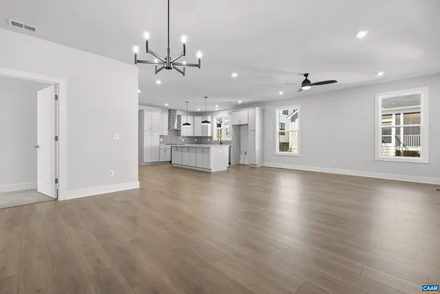 an empty room with wooden floor windows and ceiling fan