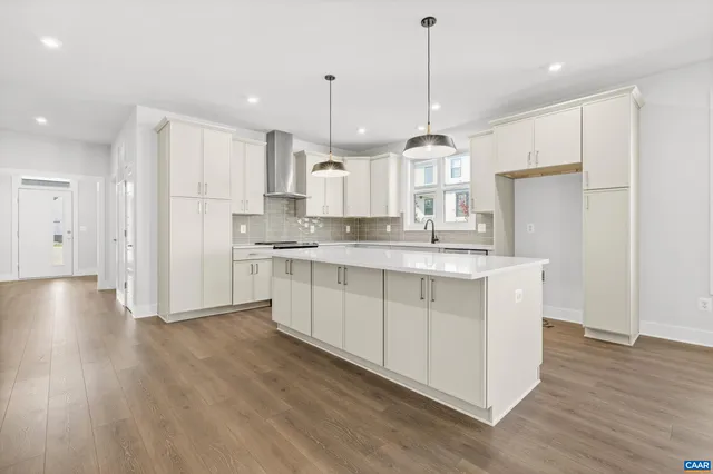 a kitchen with stainless steel appliances granite countertop a refrigerator a sink dishwasher a stove and white cabinets with wooden floor