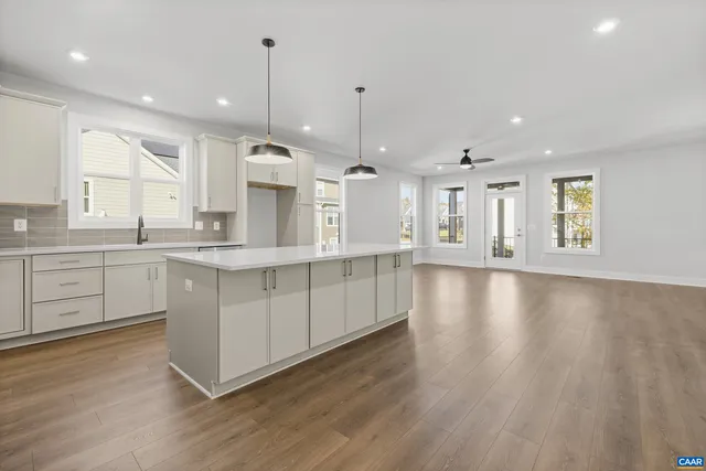 a large kitchen with granite countertop a stove a sink a center island and a wooden floor