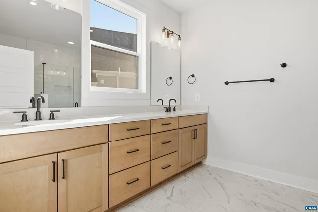 a bathroom with a double vanity sink and mirror with window